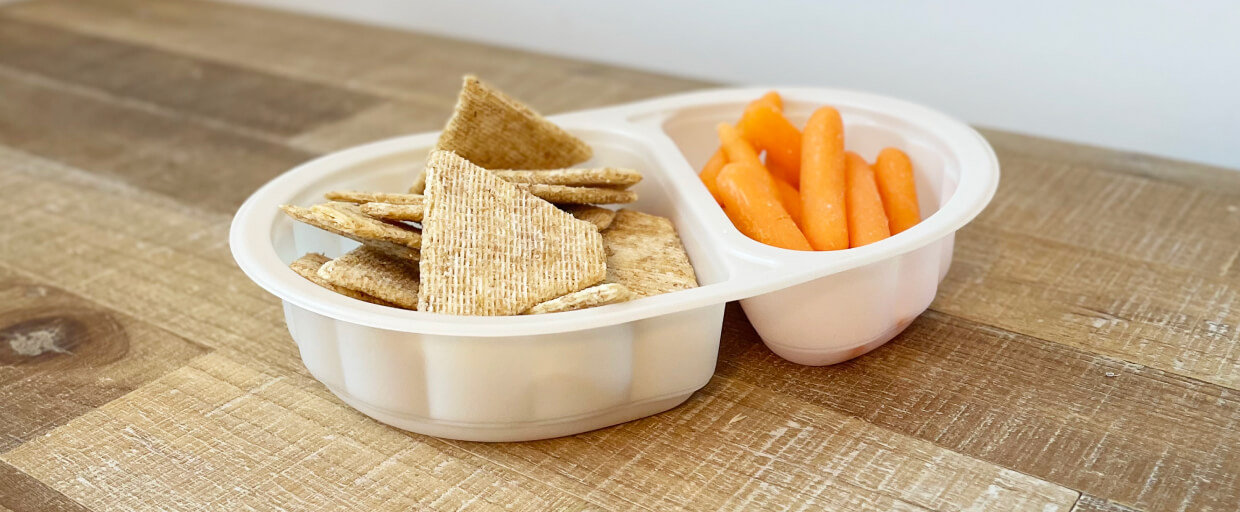 A food container made from Verde's bioresins filled with crackers and carrots